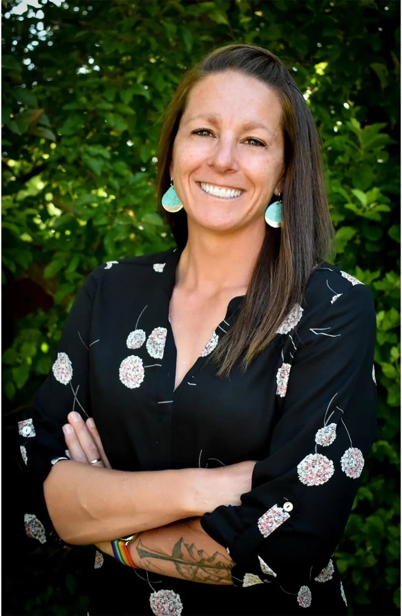 Dr. Ricki Walker smiling outdoors in front of green trees